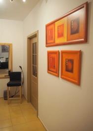 Úzká předsíň s dlažbou, světlými stěnami a moderními obrazy.