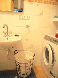 Malá koupelna s dlažbou, moderní umyvadlo, vestavěná pračka, světlé obklady.